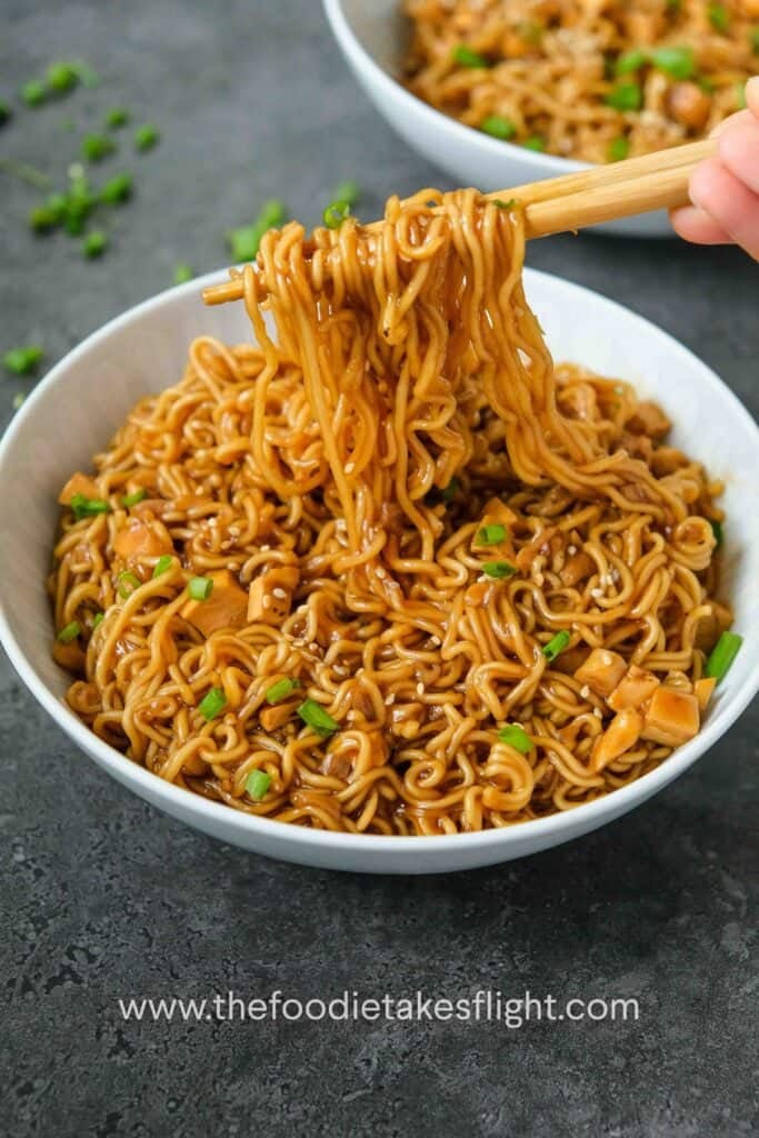 A bowl of instant ramen noodles in a thick sauce with spring onions