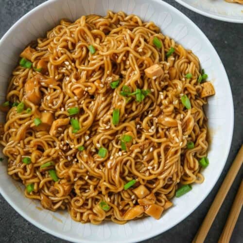 A bowl of instant ramen noodles in a thick sauce with spring onions