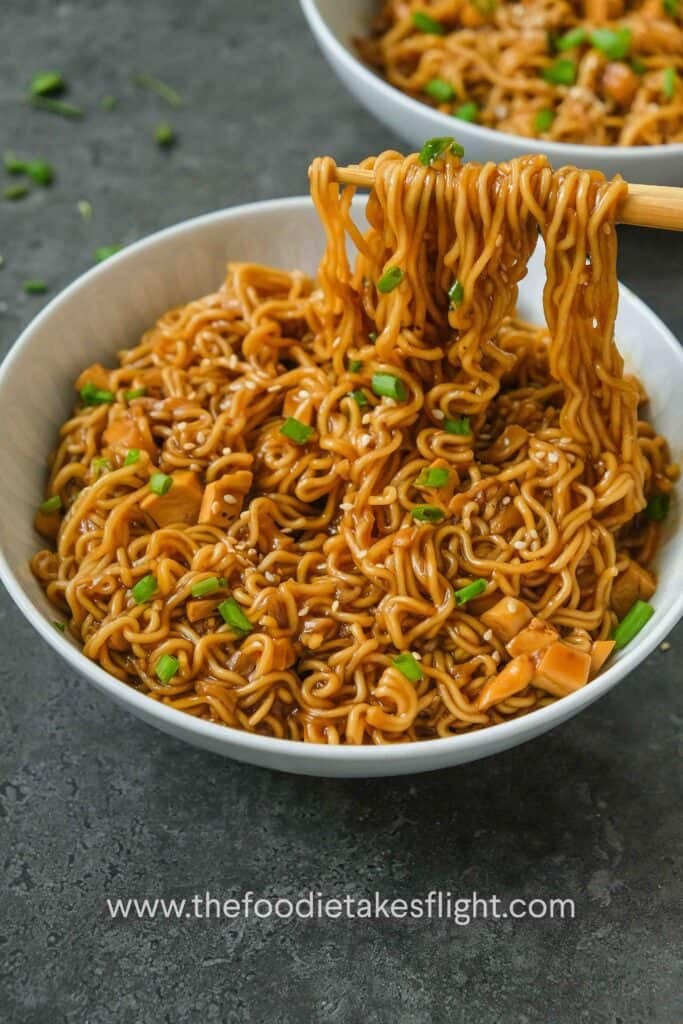 A bowl of instant ramen noodles in a thick sauce with spring onions