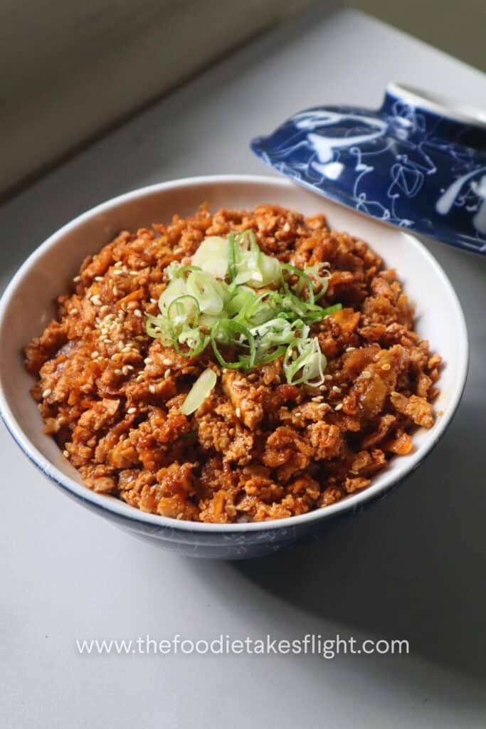 A bowl with rice and shredded tofu bulgogi plus sliced green onions