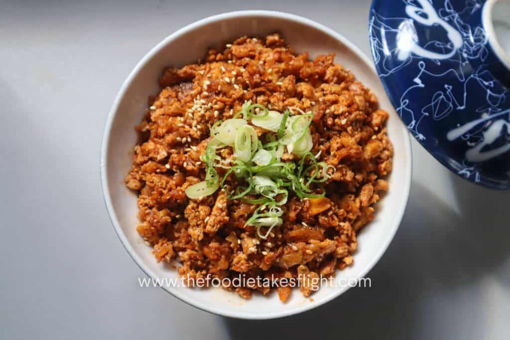 A bowl with rice and shredded tofu bulgogi plus sliced green onions