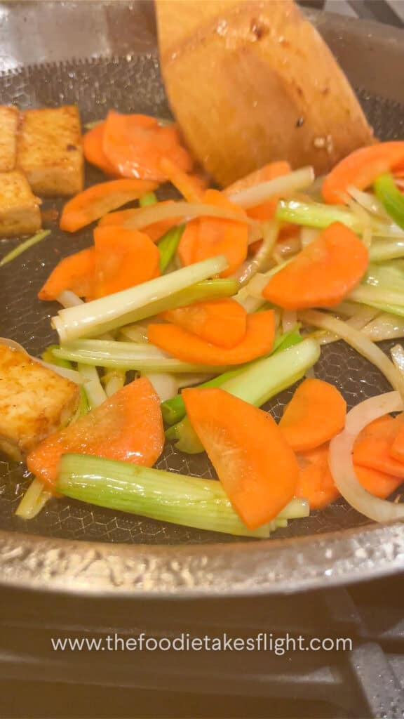 stir-frying onions and carrots with tofu