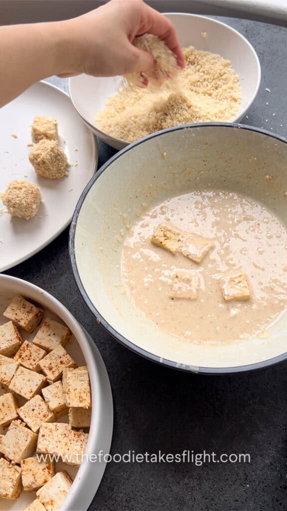 dipping tofu in the batter and coating in breadcrumbs