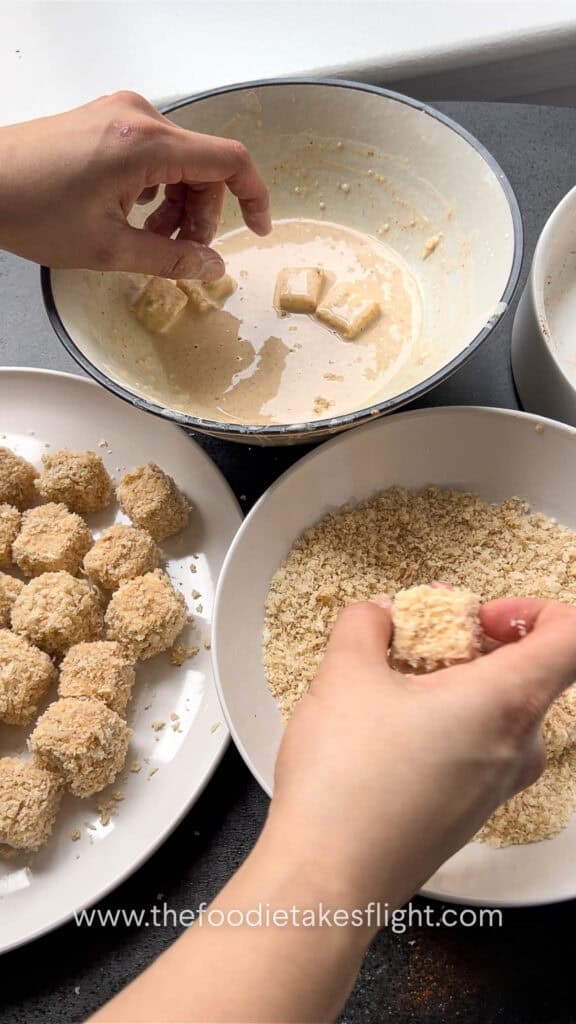dipping tofu in the batter and coating in breadcrumbs