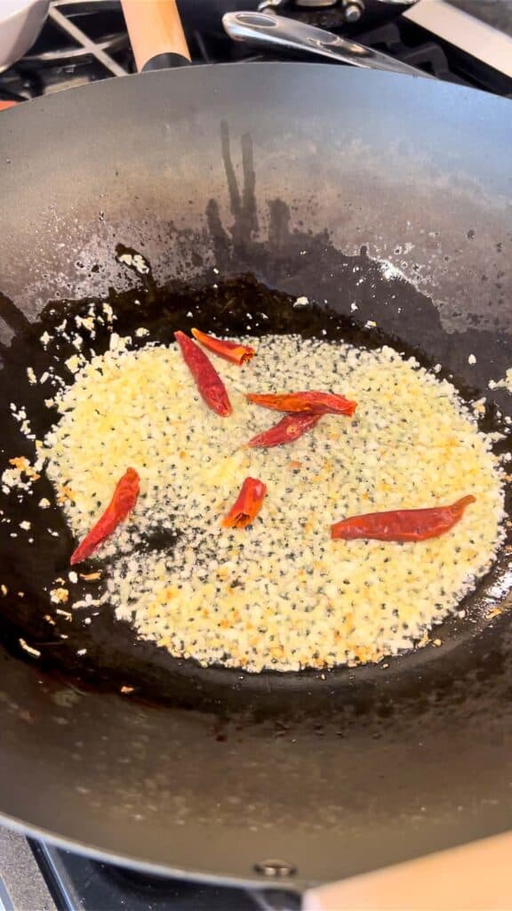 stir frying ginger and garlic with dried chiles in wok