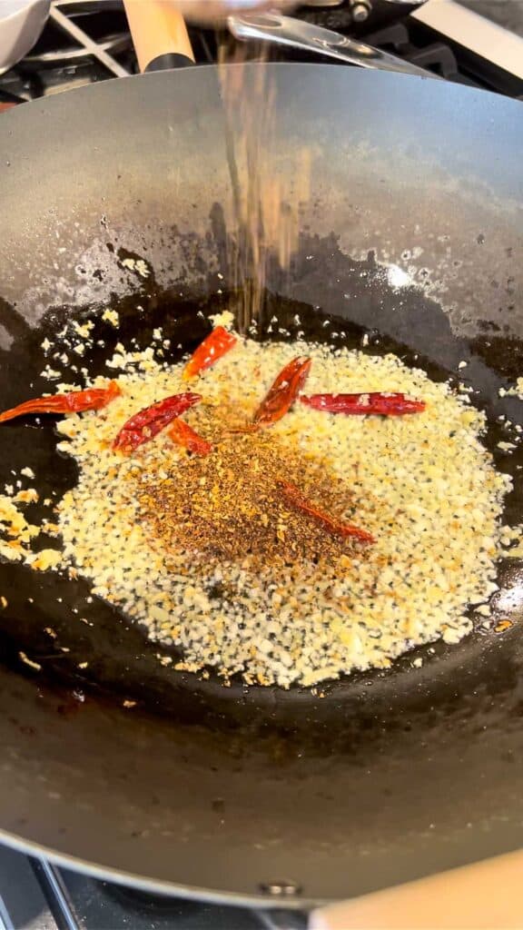 stir frying ginger, garlic, with dried chiles and Sichuan peppercorn in wok