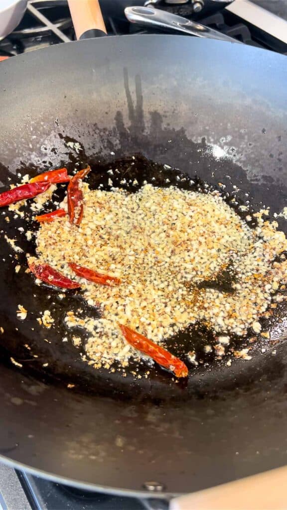 stir frying ginger, garlic, with dried chiles and Sichuan peppercorn in wok