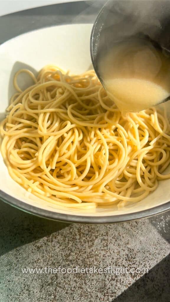pouring roasted garlic miso broth into cooked ramen noodles