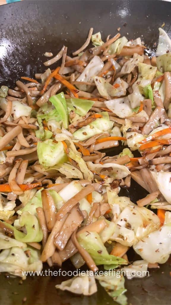 stir frying mushroom, cabbage, and carrot in aromatics