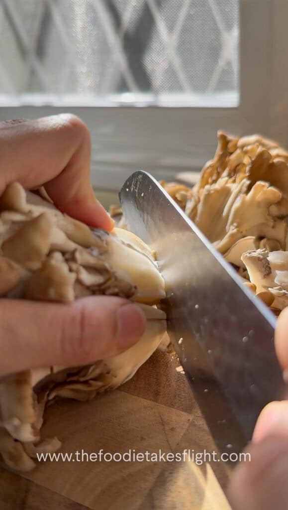 slicing resh maitake or hen of the wood mushrooms