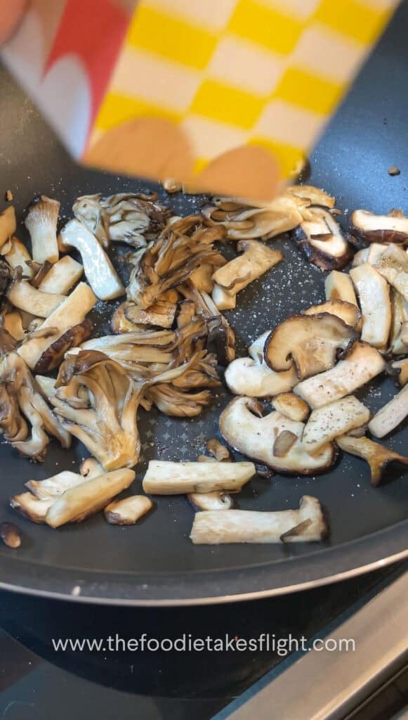 Sliced mushrooms and onions sautéing in vegan butter with steam rising from the skillet