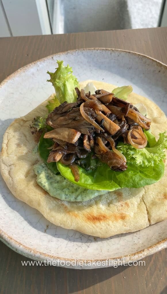 Pita bread topped with lettuce, mushrooms