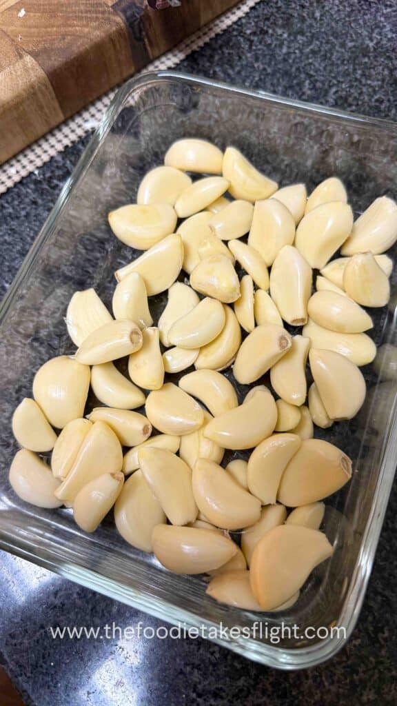 Peeled garlic cloves arranged in a small oven-safe bowl, sprinkled with salt and herbs