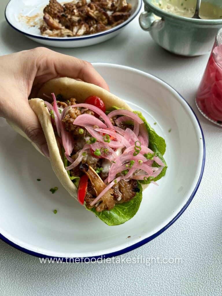 Pita wraps filled with roasted miso cauliflower, lettuce, tomatoes, pickled onions, and a drizzle of roasted garlic mayo