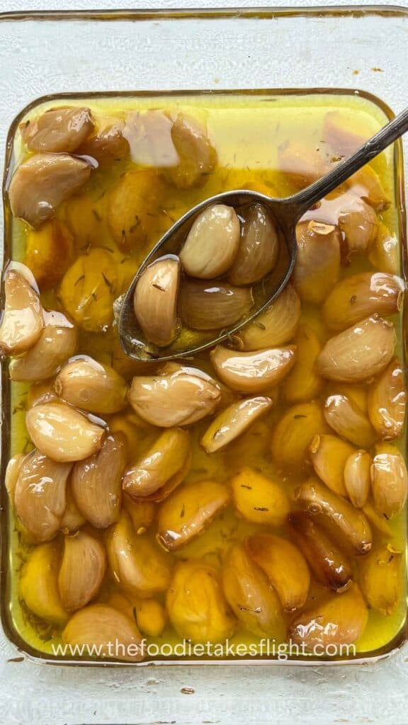 Soft, golden garlic cloves glistening in infused oil after roasting
