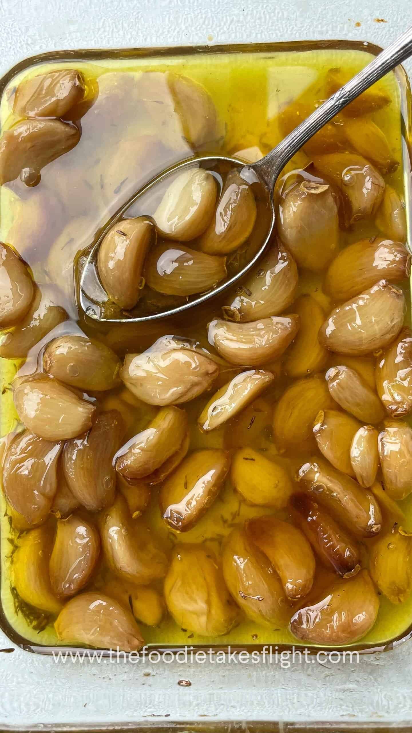 Soft, golden garlic cloves glistening in infused oil after roasting