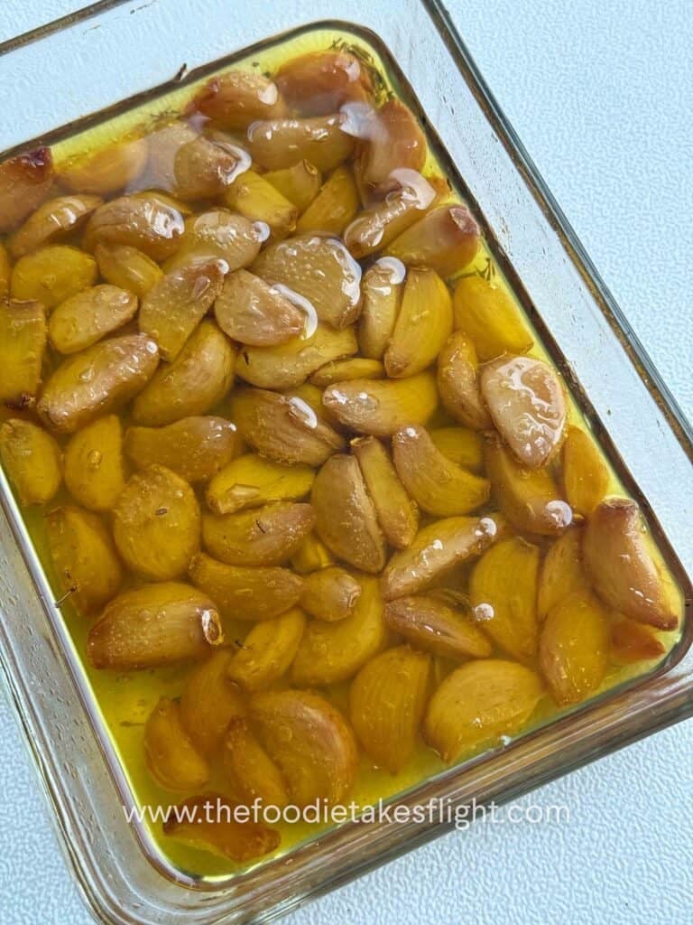 Soft, golden garlic cloves glistening in infused oil after roasting