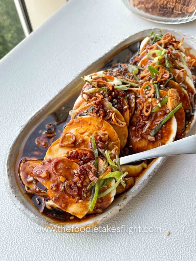 Silken tofu topped with sizzling shallot garlic oil, crispy shallots, sliced scallions, chili oil, and sesame seeds