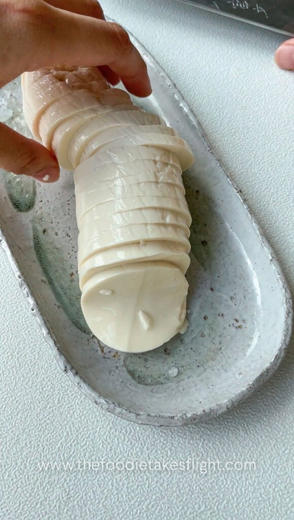 Silken tofu being portioned into thick slabs, showing its smooth and delicate texture
