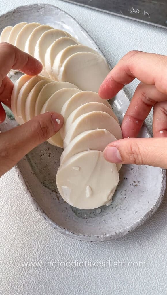 Silken tofu being portioned into thick slabs, showing its smooth and delicate texture