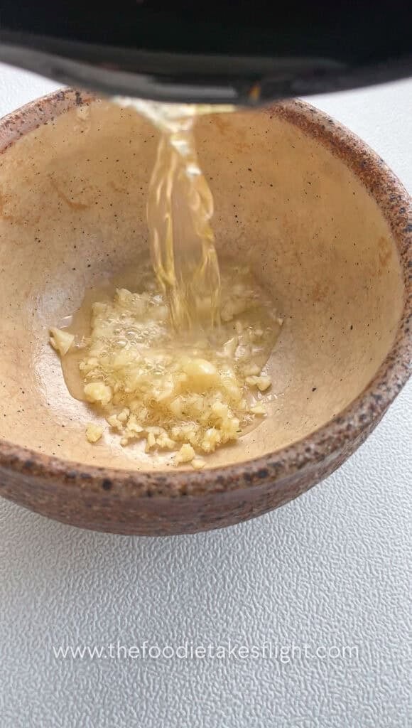 pouring hot shallot oil in the bowl of minced garlic