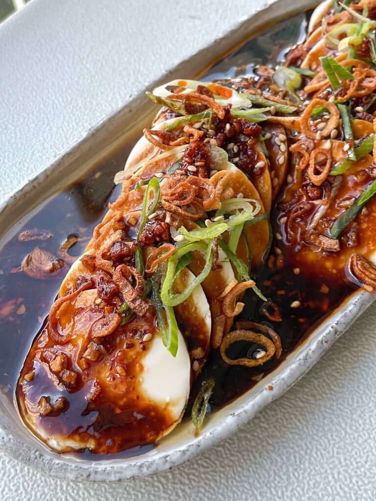 silken tofu topped with shallot garlic oil, crispy shallots, sliced scallions, chili oil, and sesame seeds