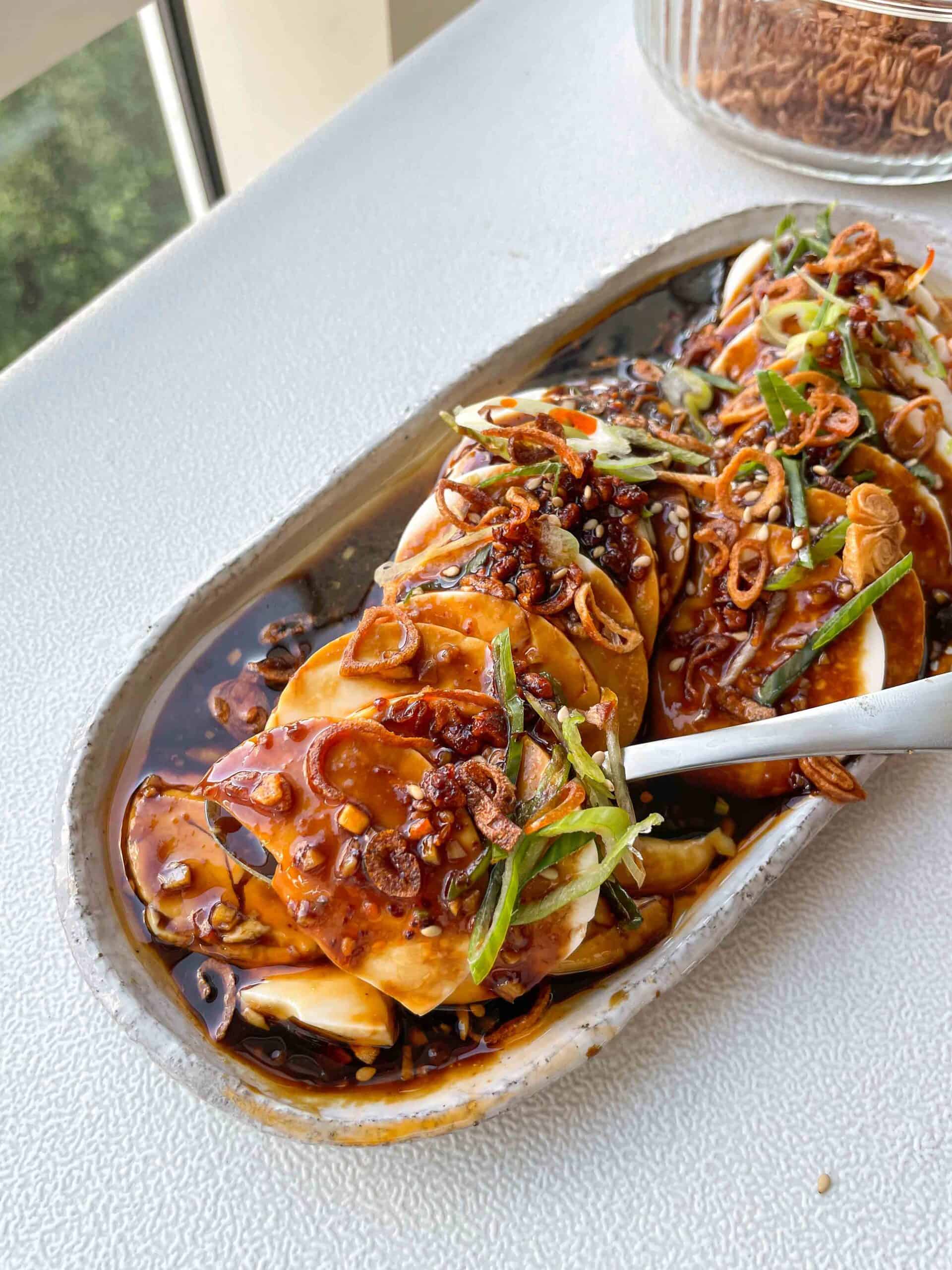 silken tofu topped with shallot garlic oil, crispy shallots, sliced scallions, chili oil, and sesame seeds