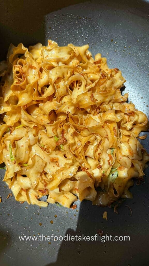glossy noodles coated in shallot oil and soy sauce in a wok
