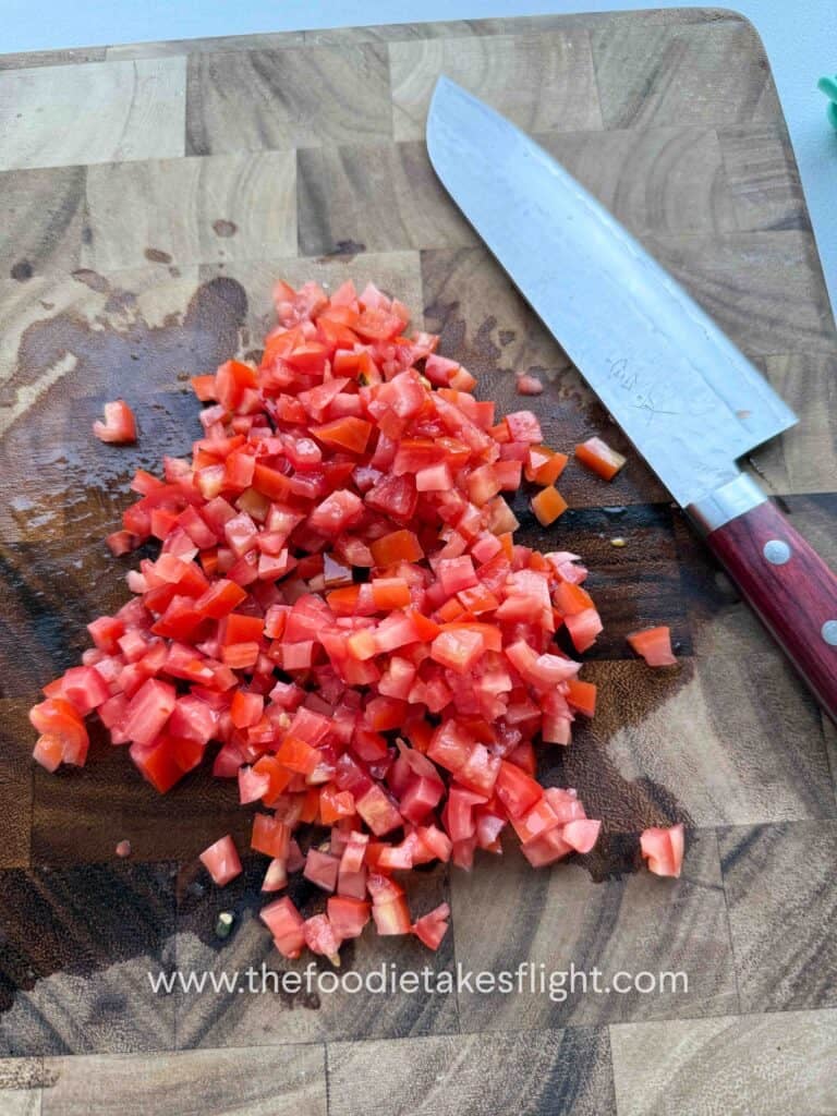 Diced red and ripe tomatoes on a wooden cutting board