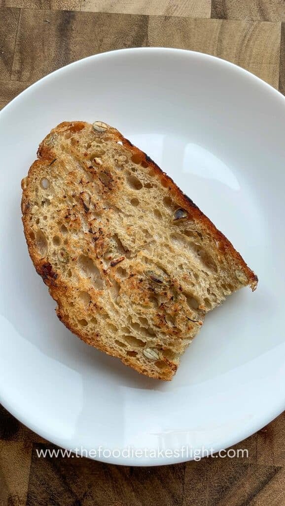 Mashed roasted garlic spread onto a slice of toasted bread with the back of a spoon