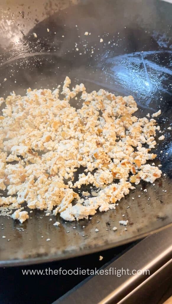 stir-frying crumbled extra firm tofu or tokwa in a pan
