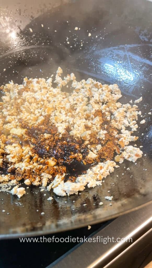 stir-frying crumbled extra firm tofu or tokwa in a pan