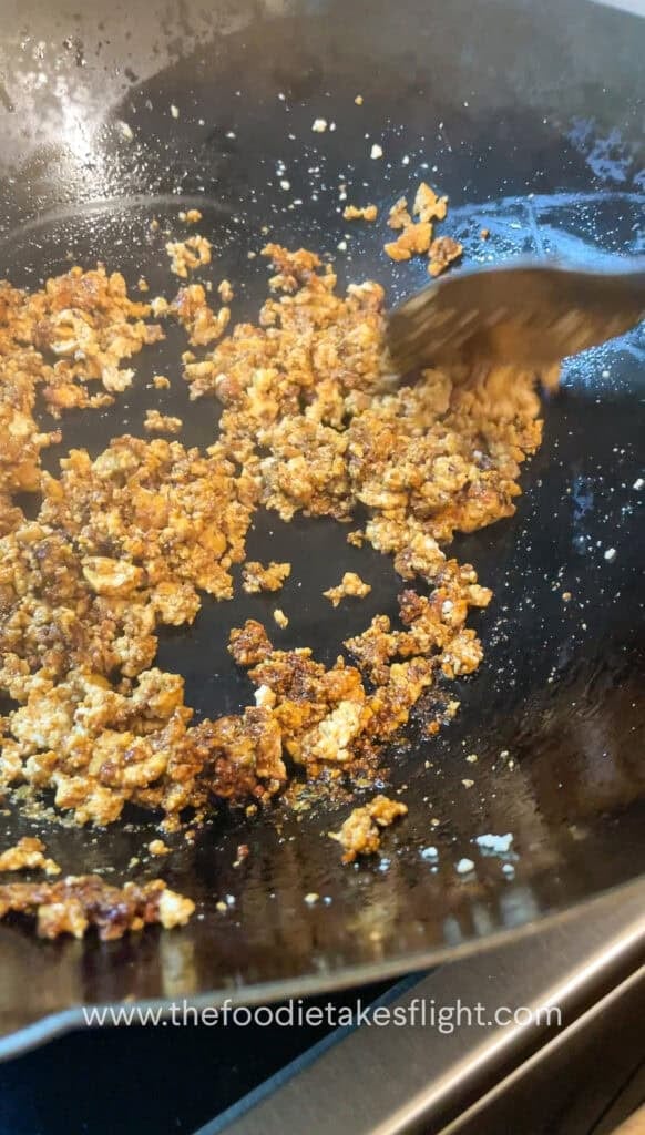 Pan of golden crumbled tofu being sautéed in infused curry leaf oil