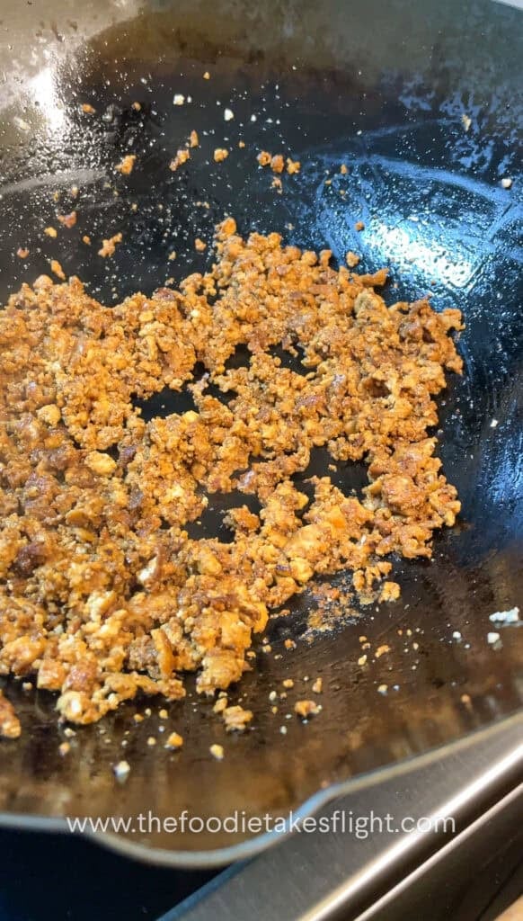 Pan of golden crumbled tofu being sautéed in infused curry leaf oil