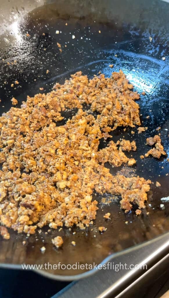 Pan of golden crumbled tofu being sautéed in infused curry leaf oil