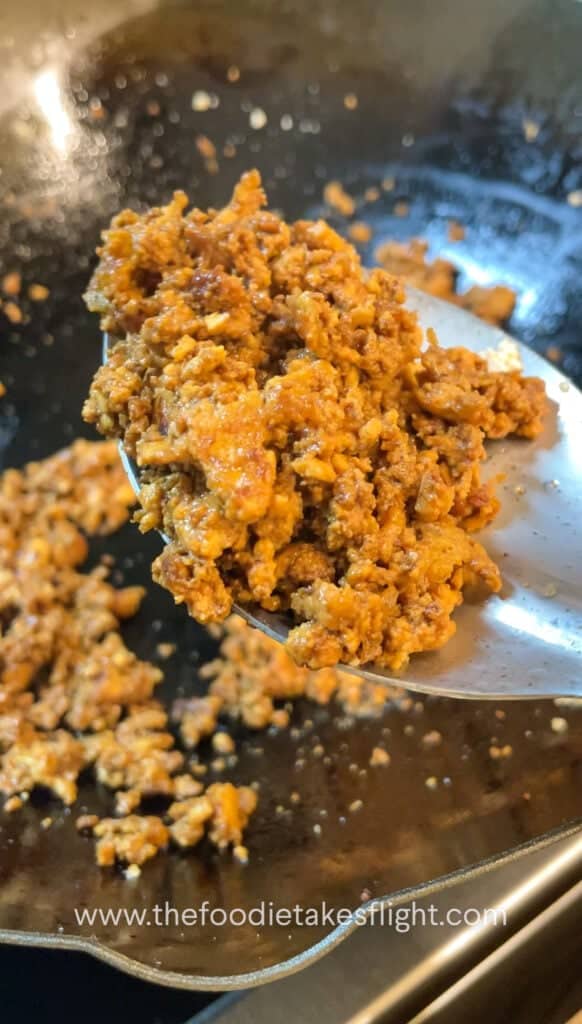 Pan of golden crumbled tofu being sautéed in infused curry leaf oil
