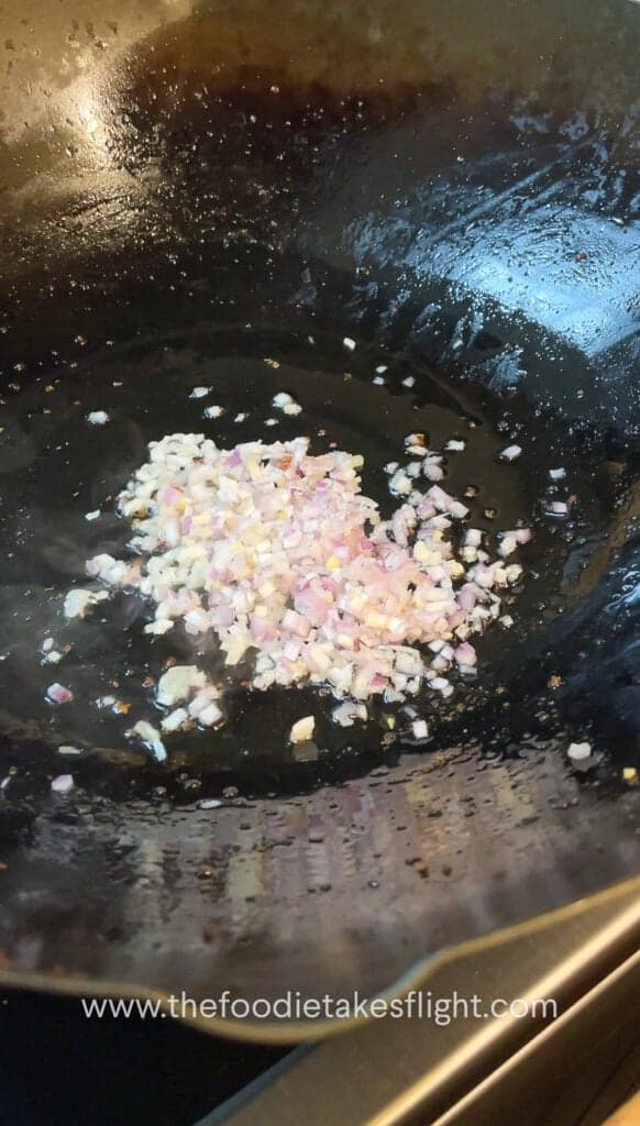 stir frying shallots, garlic, and onion in oil in a wok