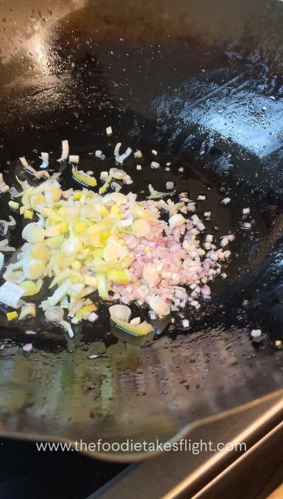 stir frying shallots, garlic, and onion in oil in a wok