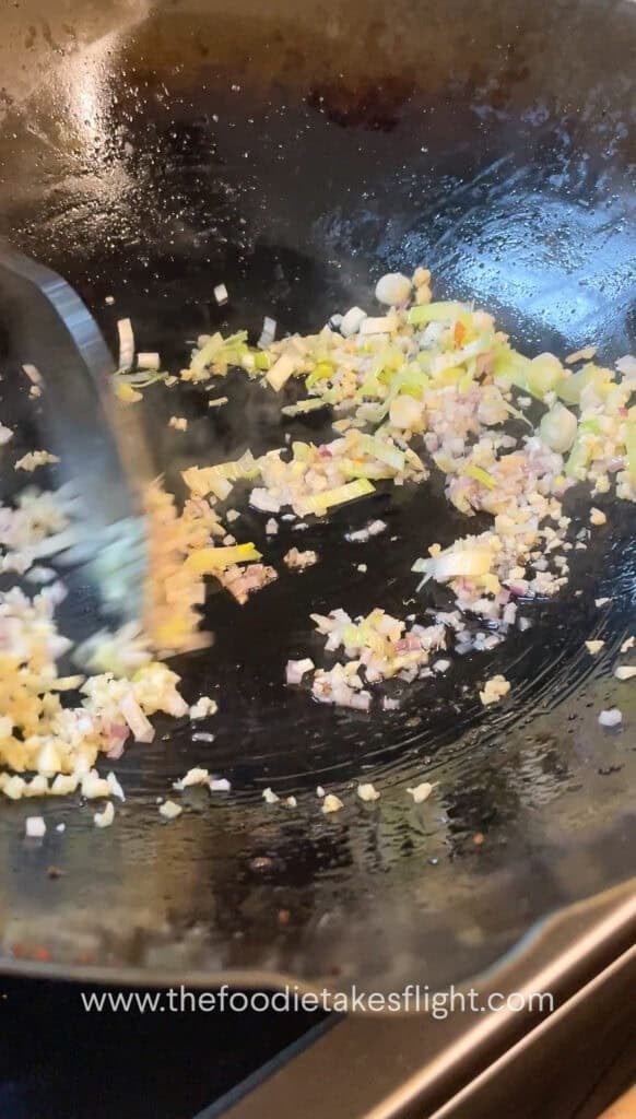 stir frying shallots, garlic, and onion in oil in a wok
