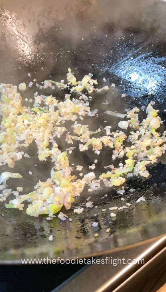 stir frying shallots, garlic, and onion in oil in a wok