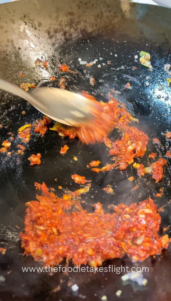 cooking down the tomato paste with aromatics in a wok