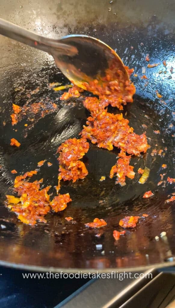 cooking down the tomato paste with aromatics in a wok