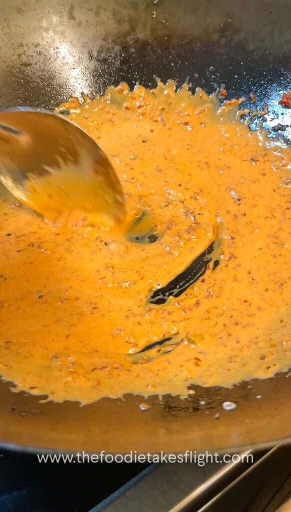 creamy tomato coconut sauce simmering in a wok