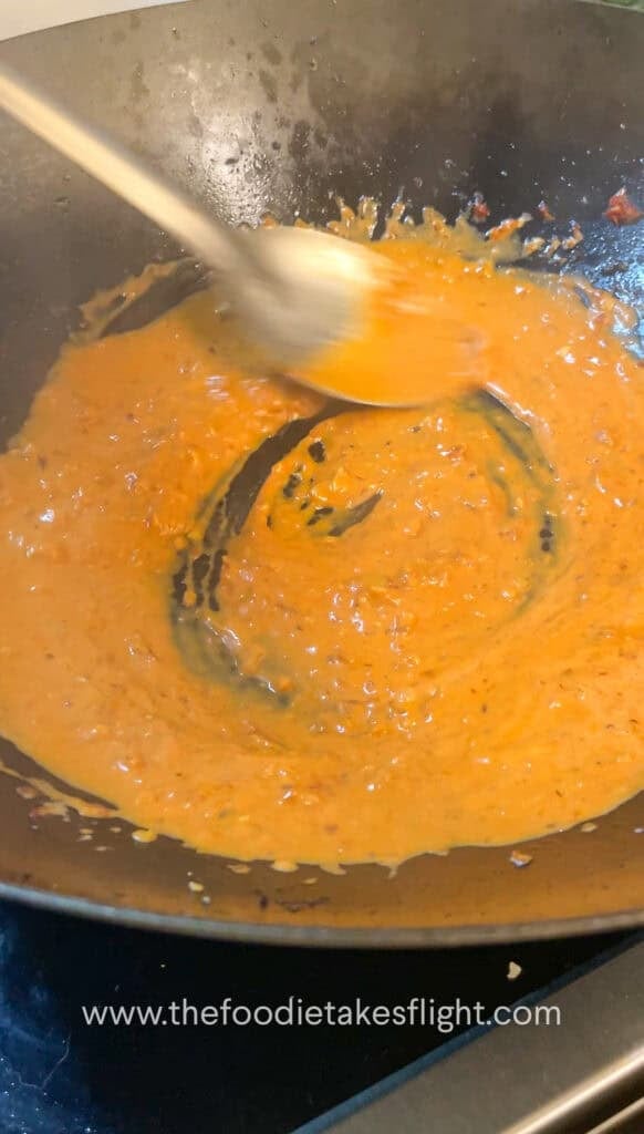 creamy tomato coconut sauce simmering in a wok