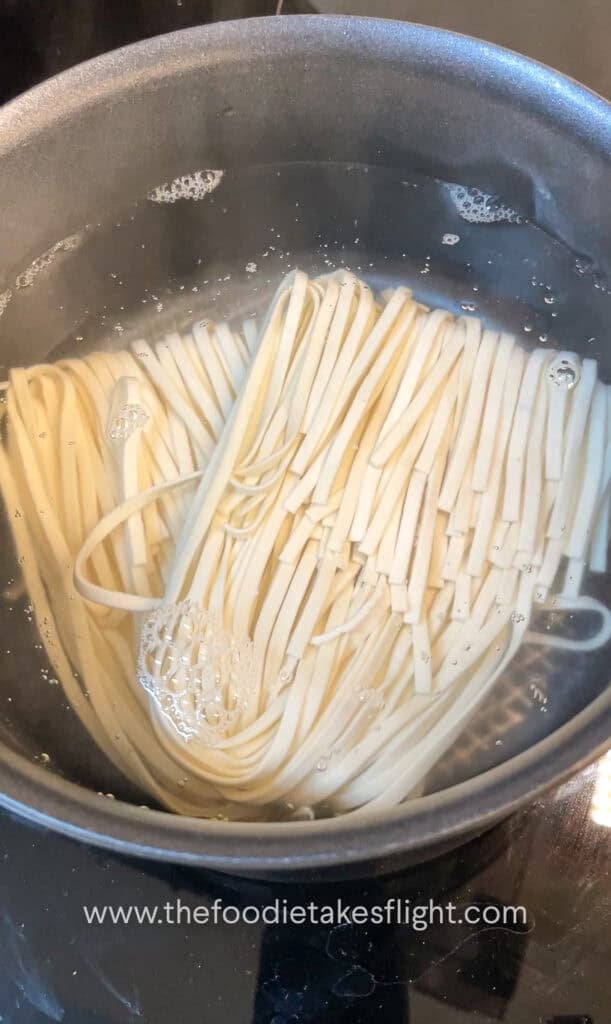 cooking wheat noodles in a pot of hot water