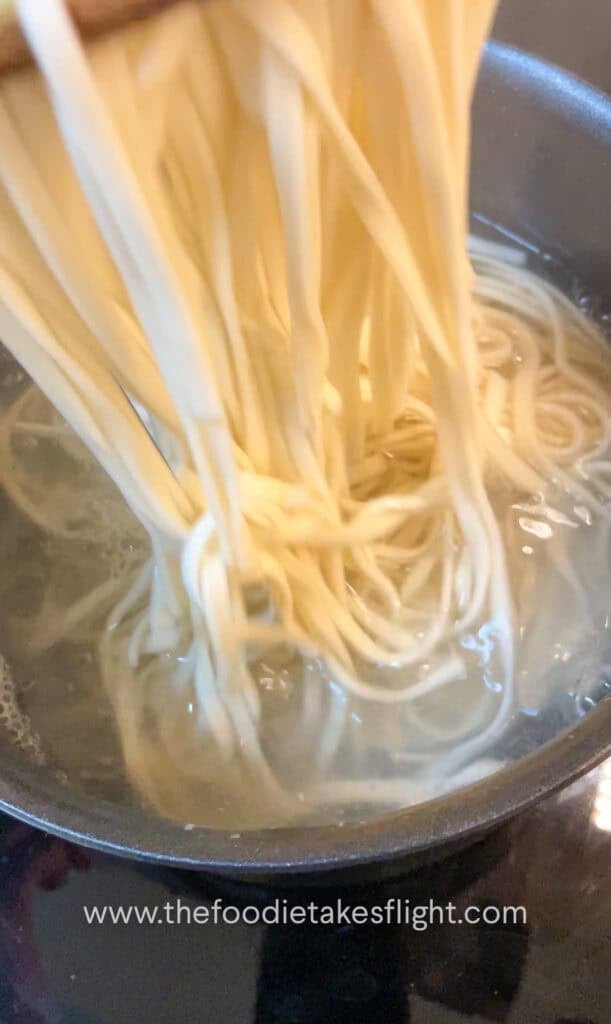 cooking wheat noodles in a pot of hot water