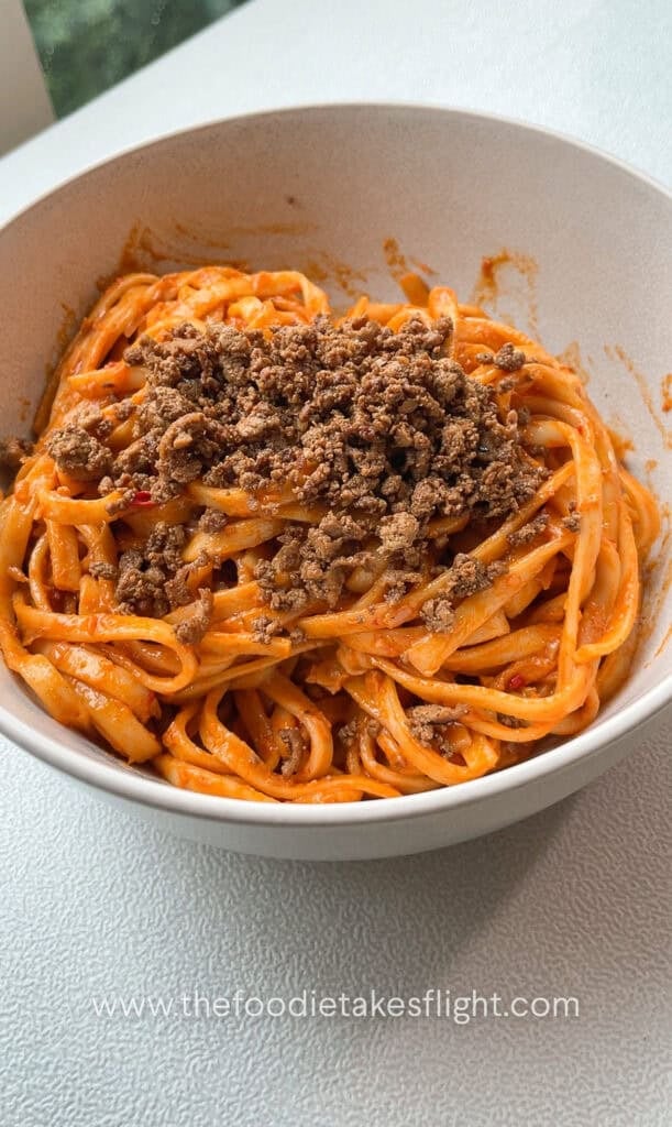creamy tomato coconut noodles topped with crumbled tofu