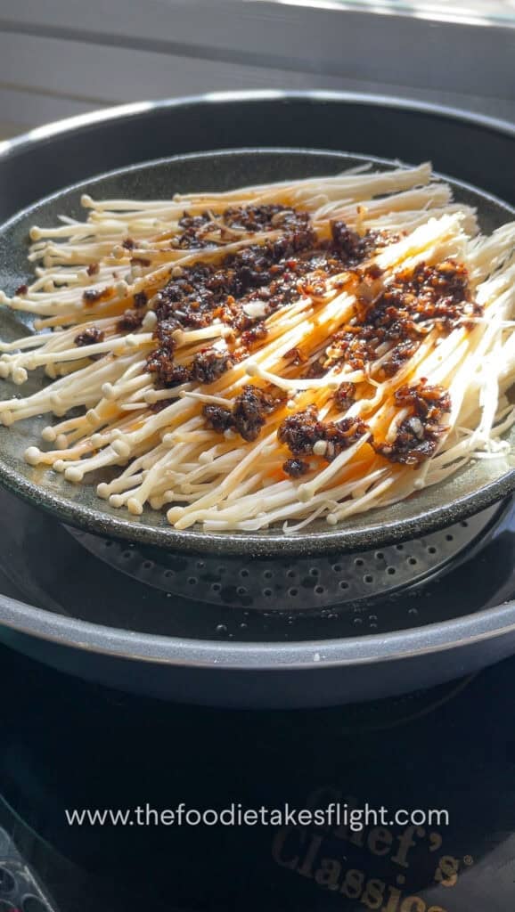 Plate of enoki mushrooms with chili garlic oil in a steamer