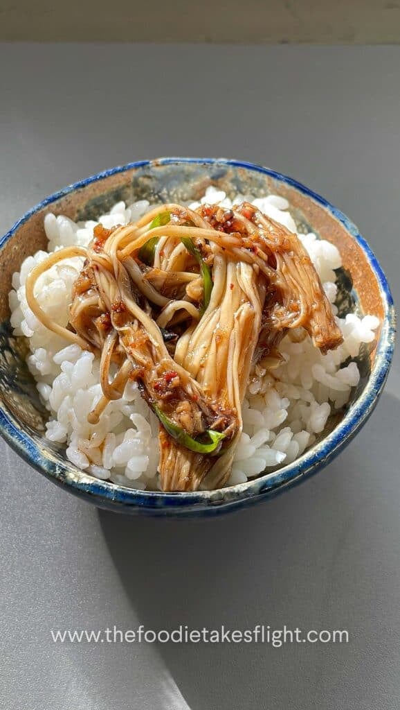 small portion of steamed enoki mushrooms over a bowl of steamed short grain rice