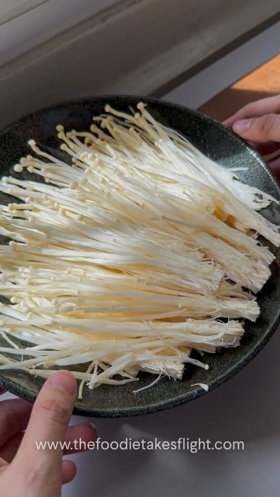 Separated enoki mushrooms arranged on a heat-proof plate before steaming